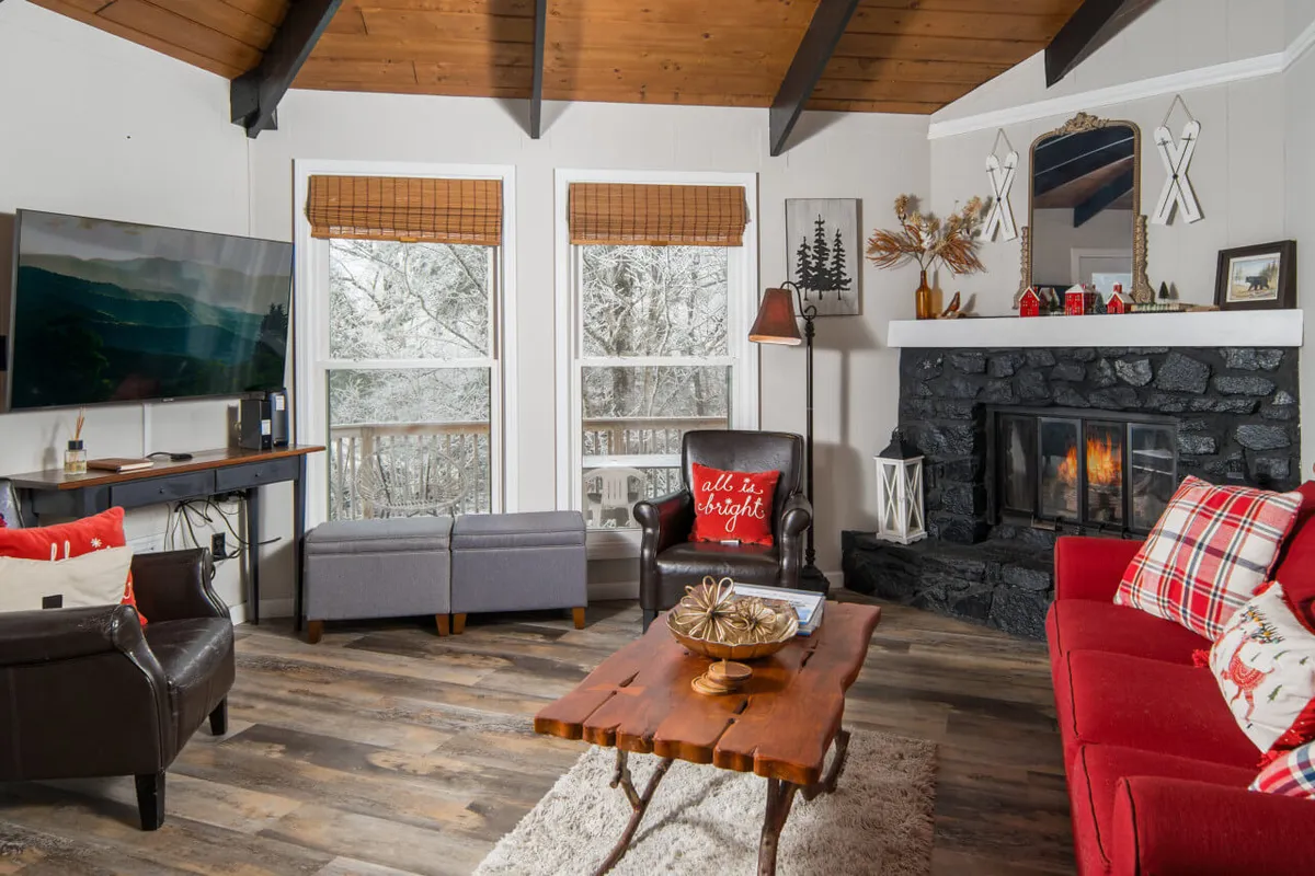 A cozy living room with a fireplace, comfortable sofa, television, and windows letting in natural light. The space feels inviting and perfect for relaxing with family members and pets after a day of adventure.