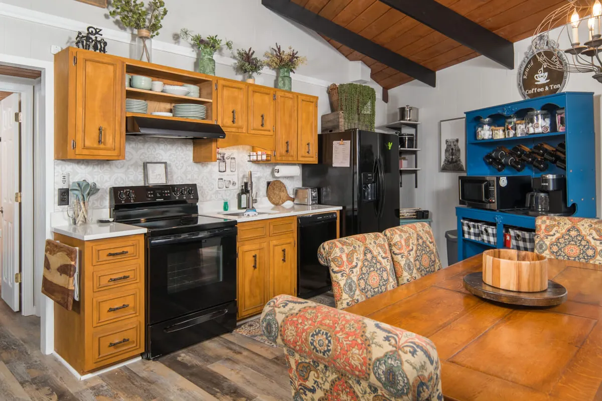 A stylish, open kitchen and dining area with a central island, black appliances, and colorful cabinetry. The space is designed for gatherings, sharing meals, and making memories after a day of exploring Beech Mountain.